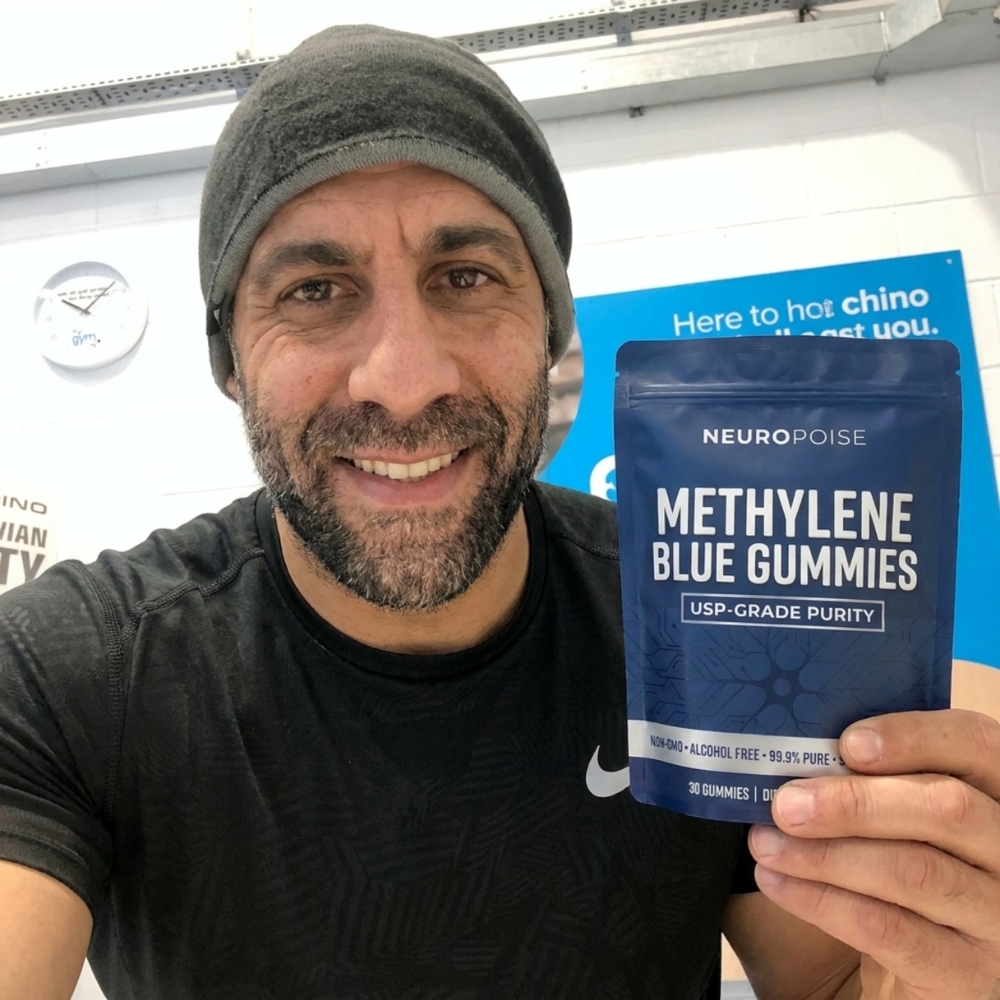 A smiling man in a beanie holds up a blue pouch of NeuroPoise Methylene Blue Gummies.