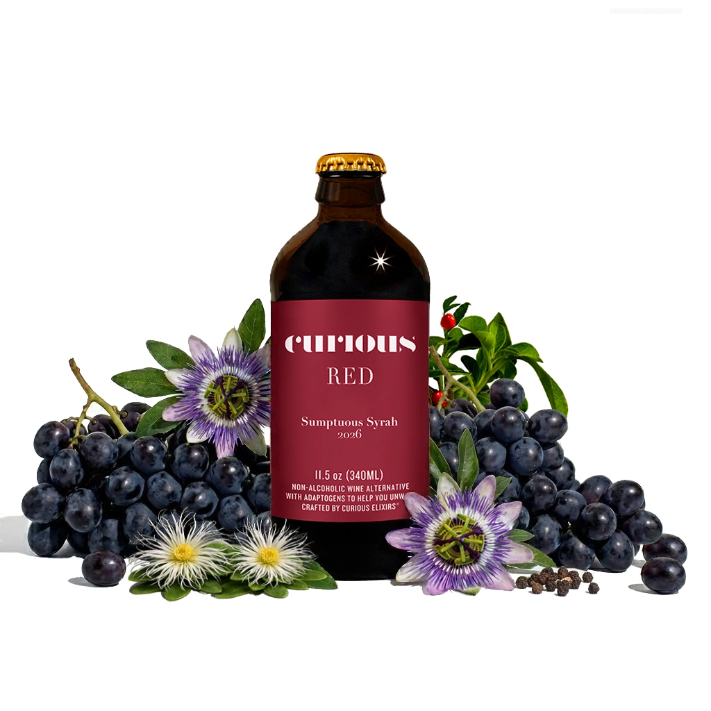 A bottle of Curious Red non-alcoholic wine alternative surrounded by grapes, passion flowers, and peppercorns on a white background.