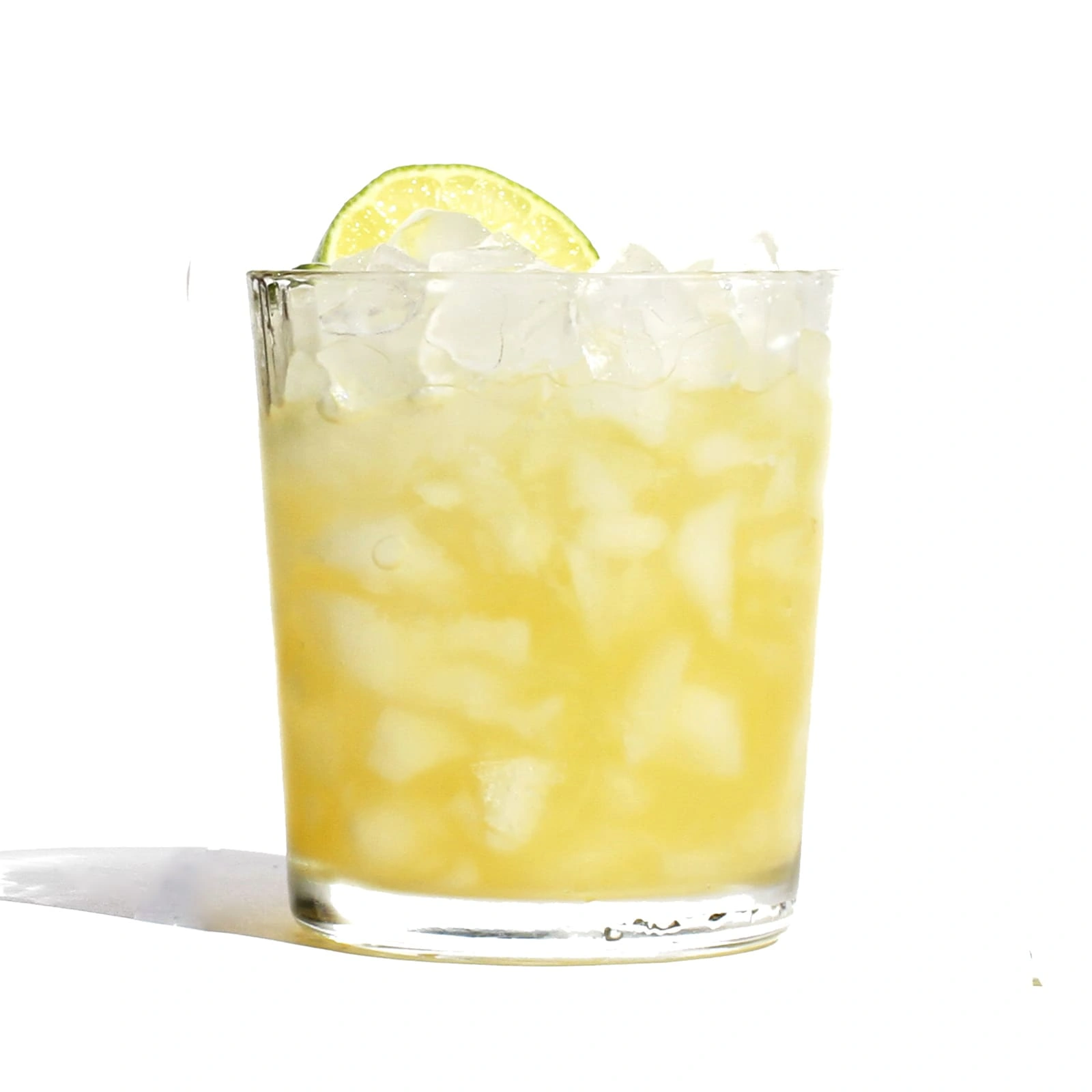 A yellow drink with crushed ice in a glass, garnished with a slice of lime.