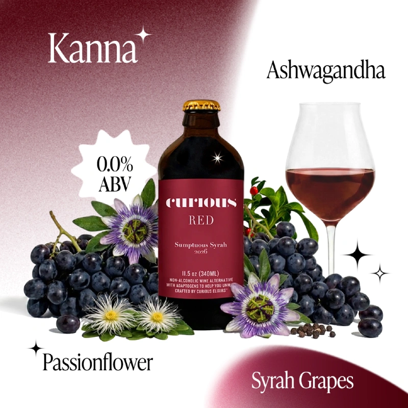 A bottle of Curious Red non-alcoholic wine sits next to a glass, surrounded by grapes and passionflowers.
