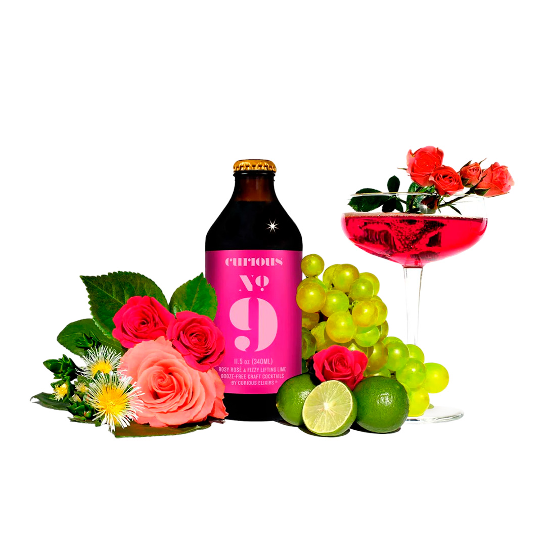A pink-labeled bottle, cocktail, roses, limes, and grapes on white background.