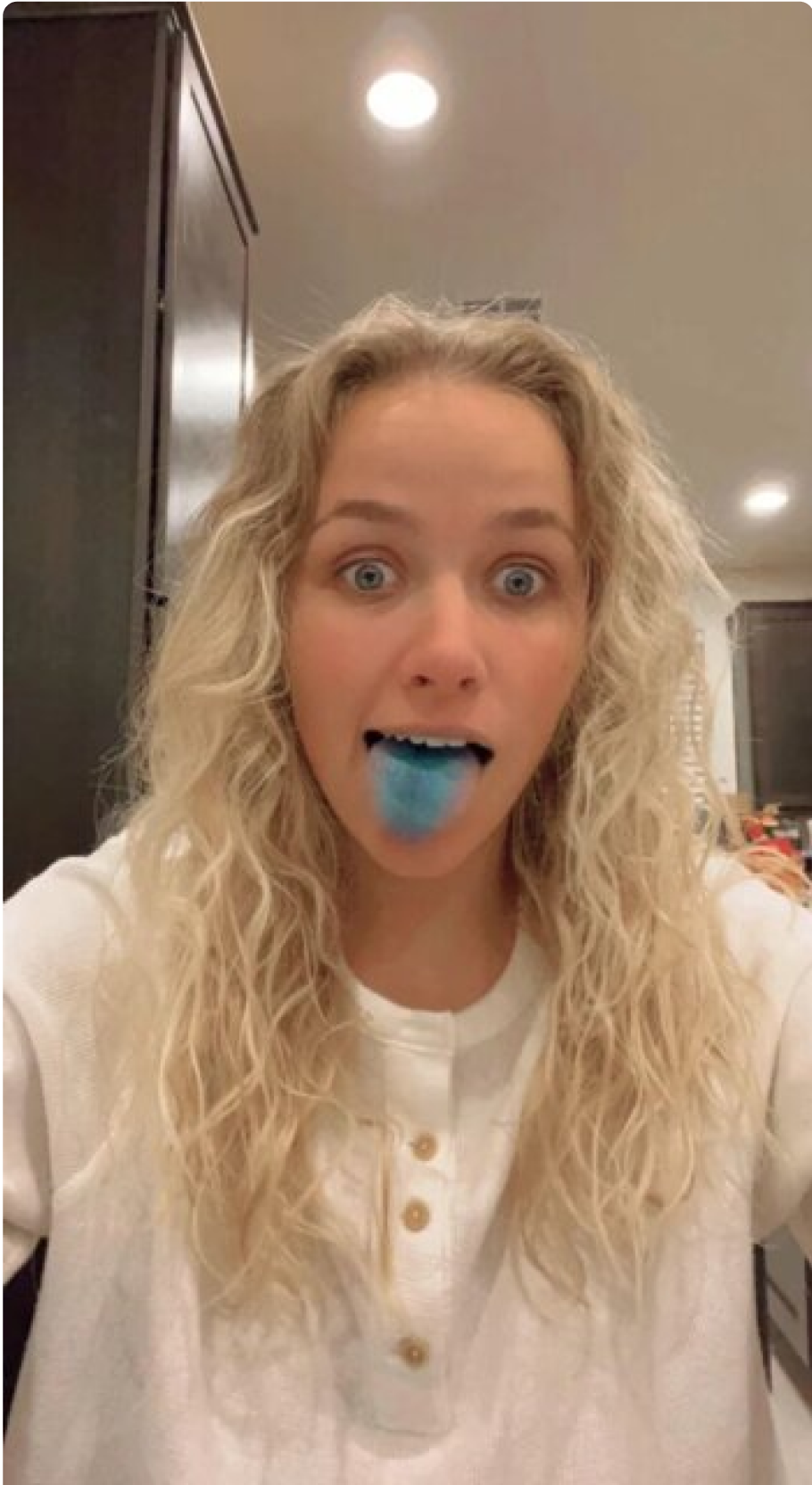 Person with curly hair showing a blue tongue.
