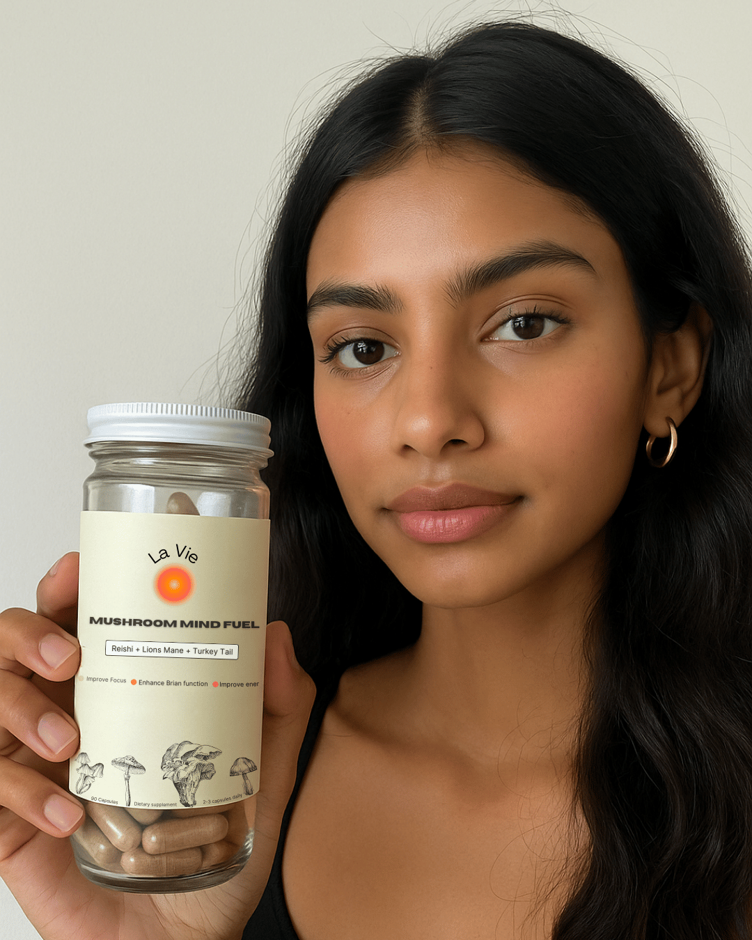 Person holding a jar labeled 'Mushroom Mind Fuel' with capsules inside.