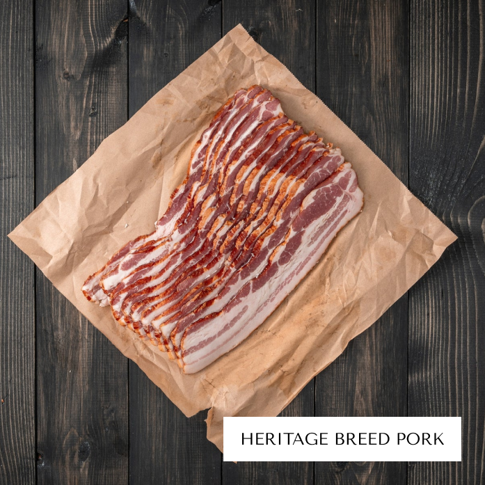 Sliced bacon on brown paper with label 'Heritage Breed Pork.'