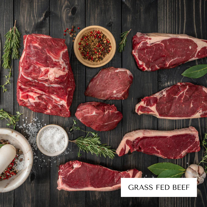 Assorted raw beef cuts with herbs and spices on a dark wooden surface.