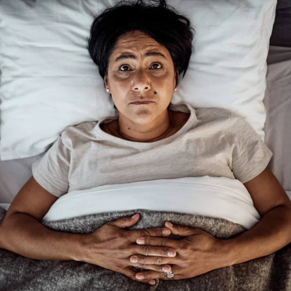 Person lying in bed with a serious expression.
