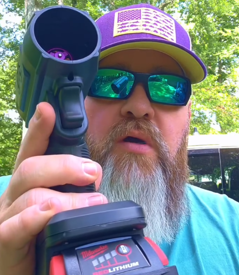 Person holding a Milwaukee M18 lithium battery tool outdoors.