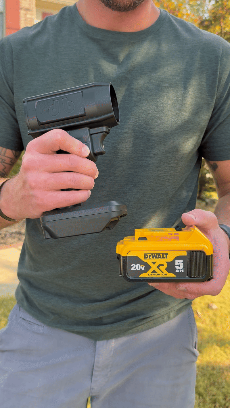 Person holding a black tool handle and yellow DeWalt battery.
