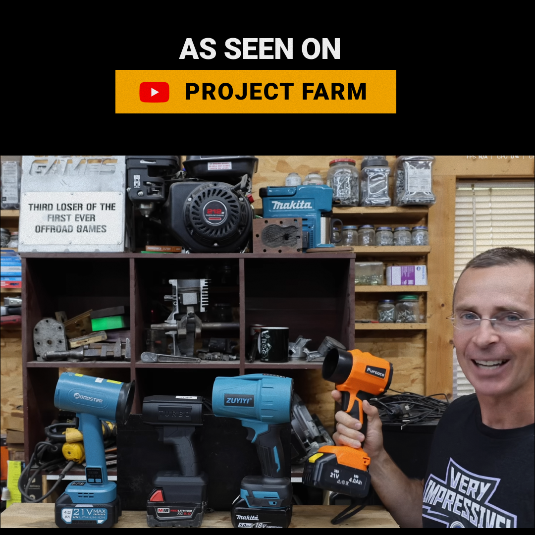 A man in a workshop holds an orange cordless heat gun, with three other models on a workbench.