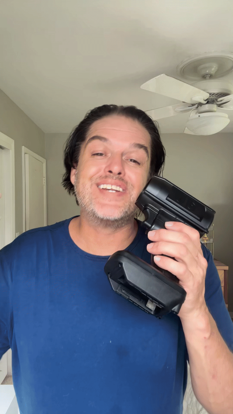 Person smiling while holding a handheld device to their face.