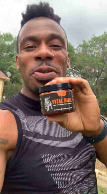 Person holding a jar labeled 'Vital Build' outdoors.