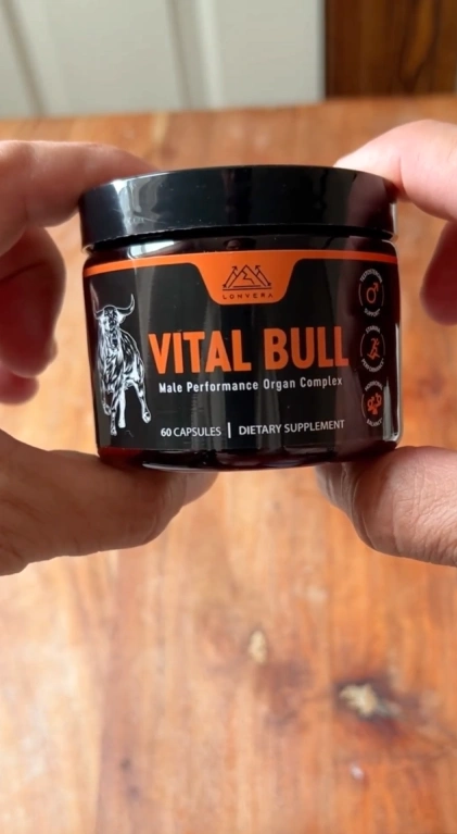 Hands holding a jar labeled 'Vital Bull' dietary supplement.