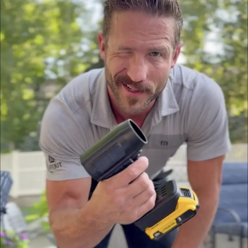 Person winking, holding a cordless power tool outdoors.