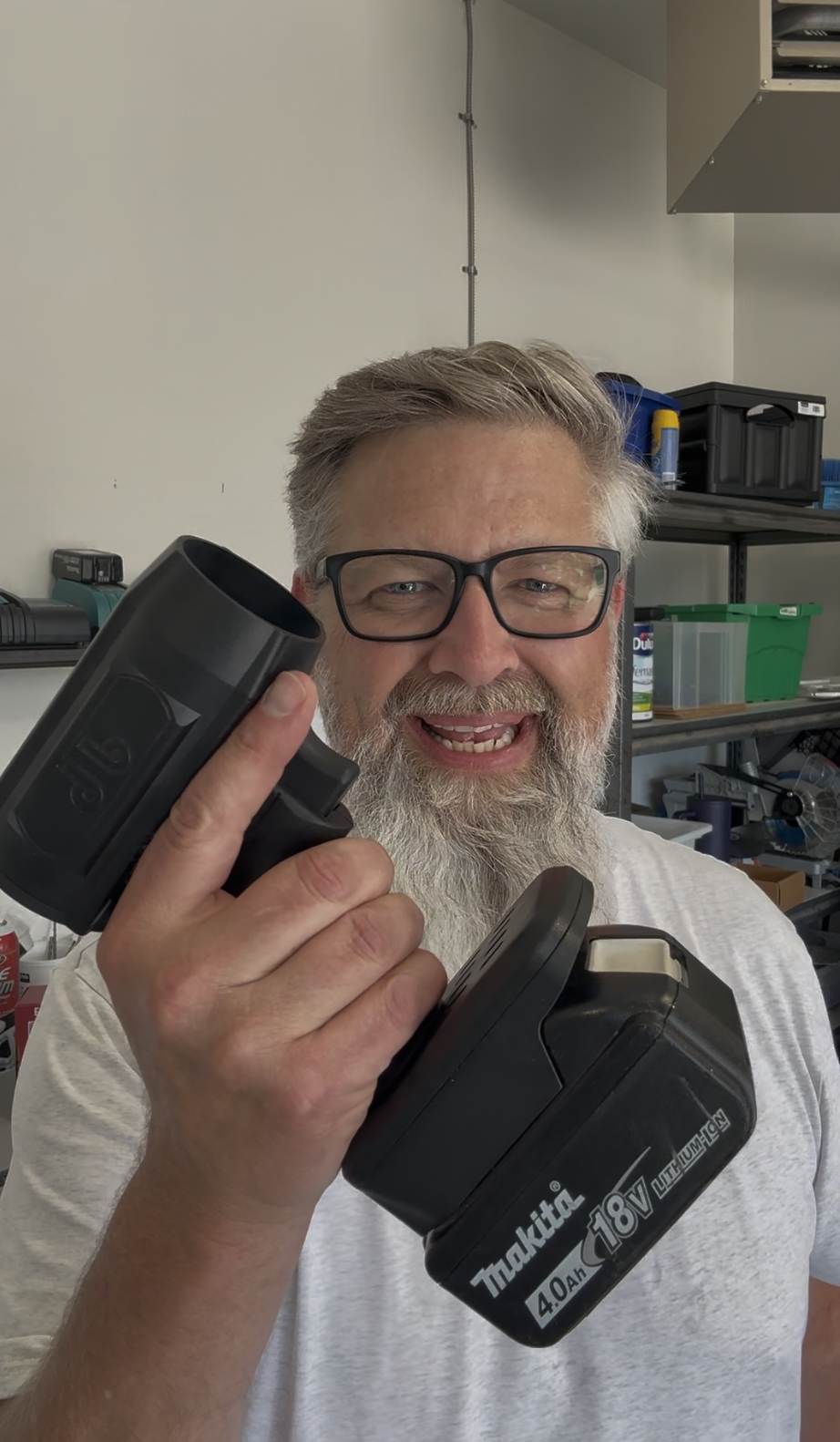 Person holding a power tool battery with shelves in the background.