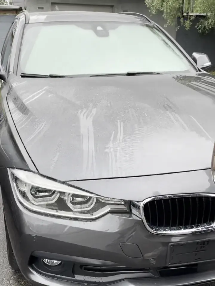 Silver car with water droplets on the hood and windshield.
