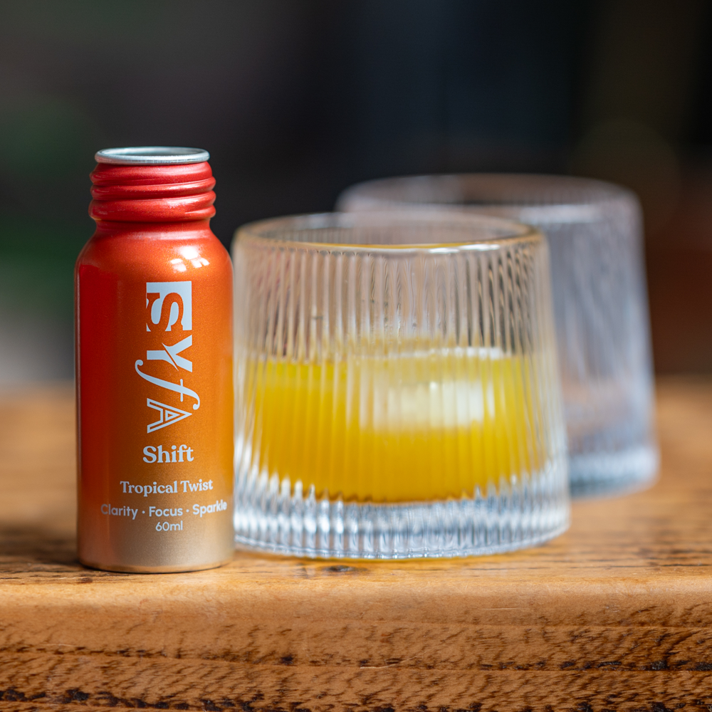 Small orange bottle labeled 'Shift' next to two glasses with yellow liquid.