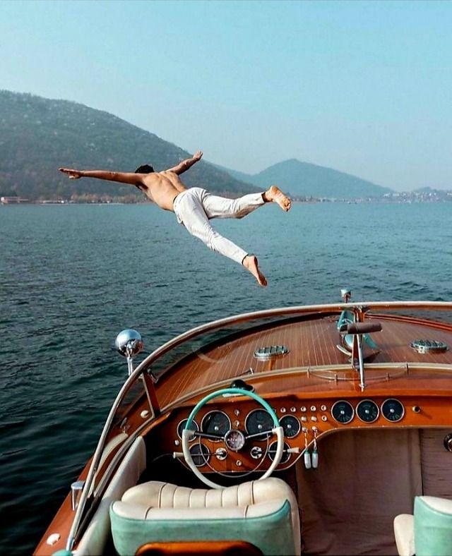 Person diving off a wooden boat into a lake.