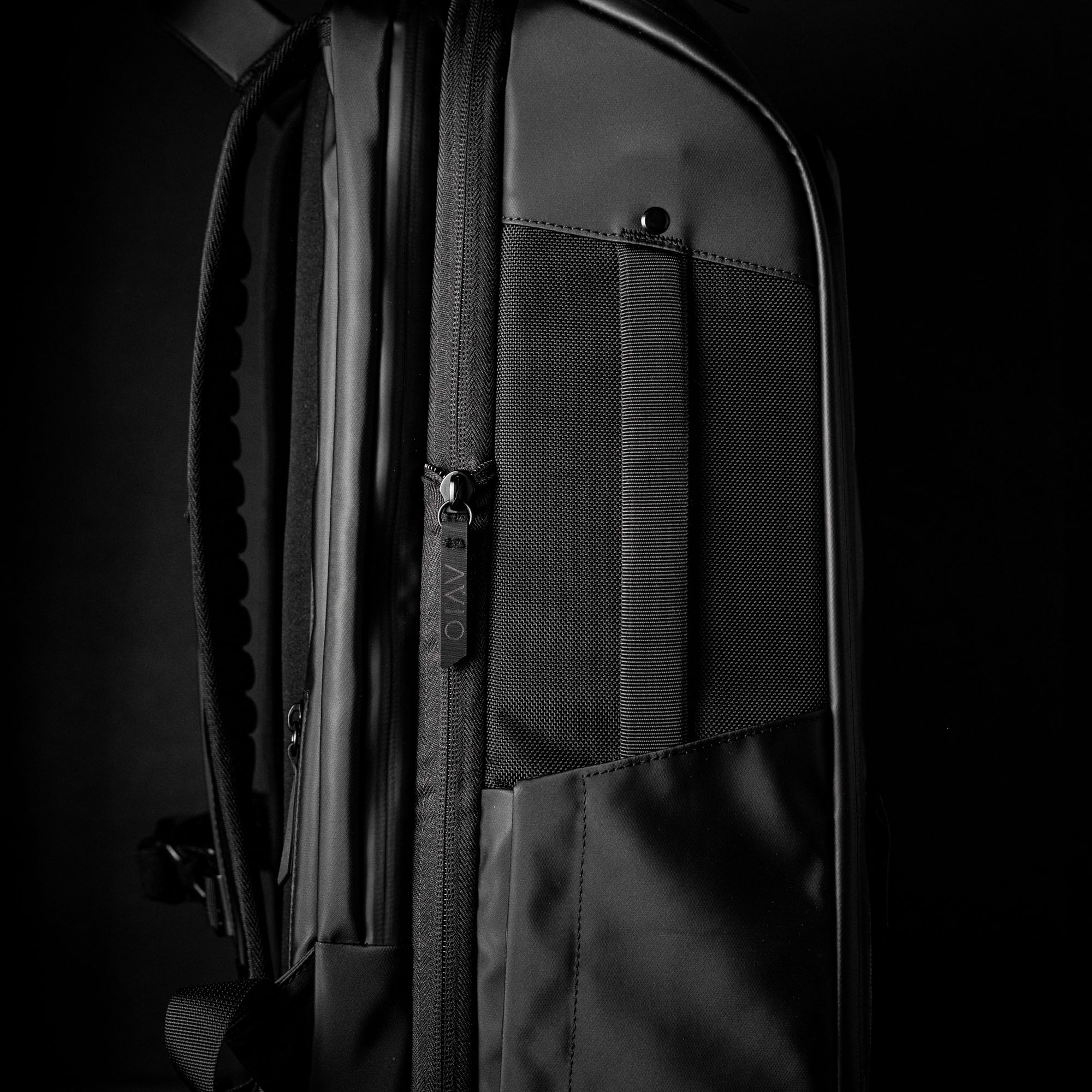 Side view of a black backpack with zippers and pockets.