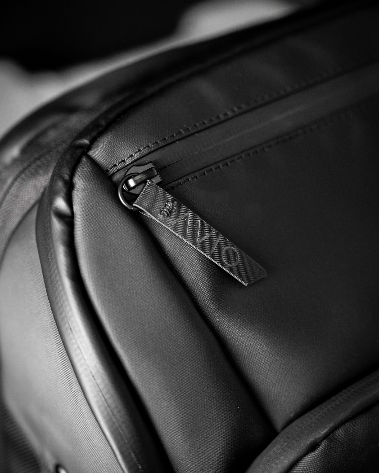 Close-up of a black backpack zipper with a branded pull tab.