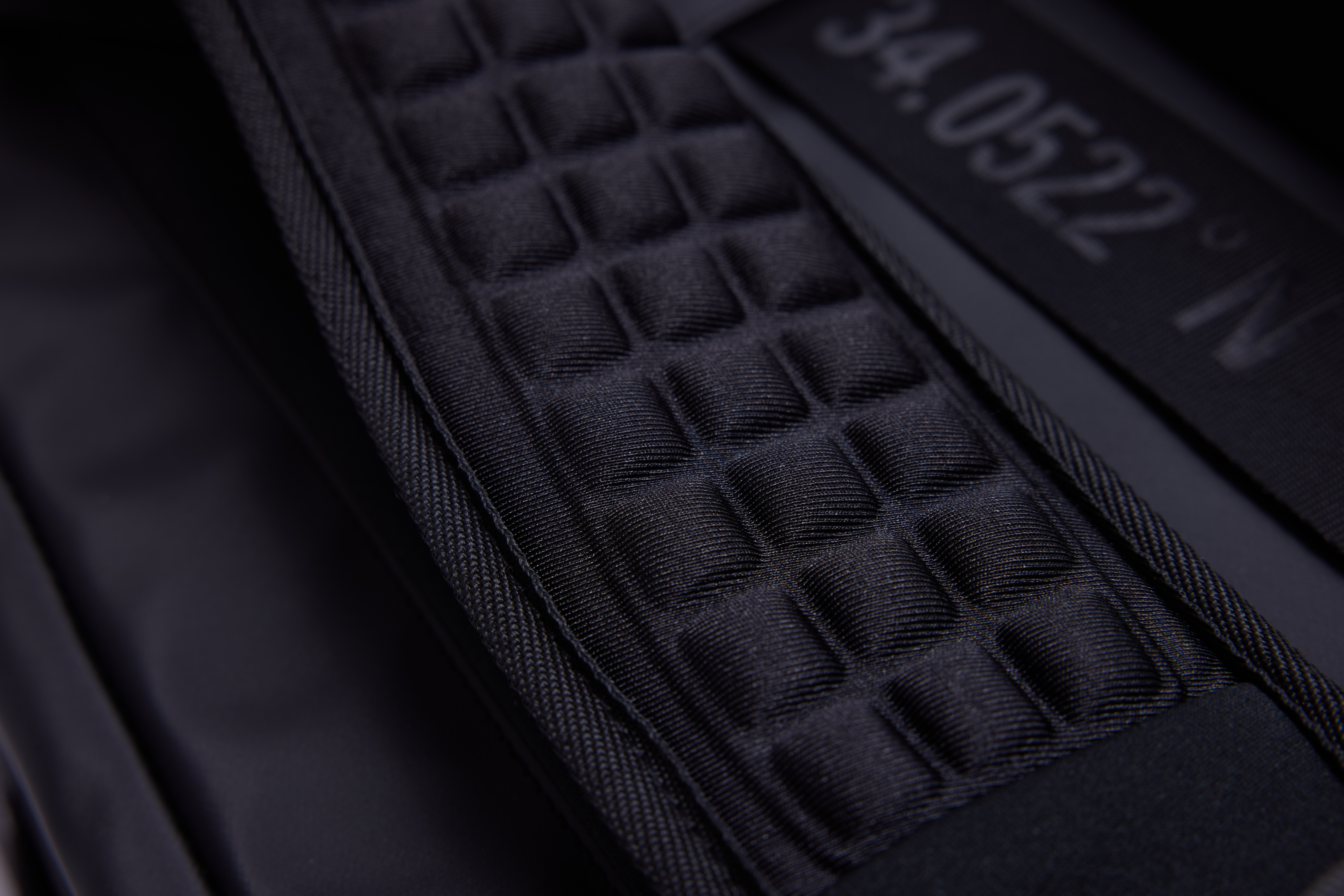 Close-up of a textured black fabric with grid pattern.