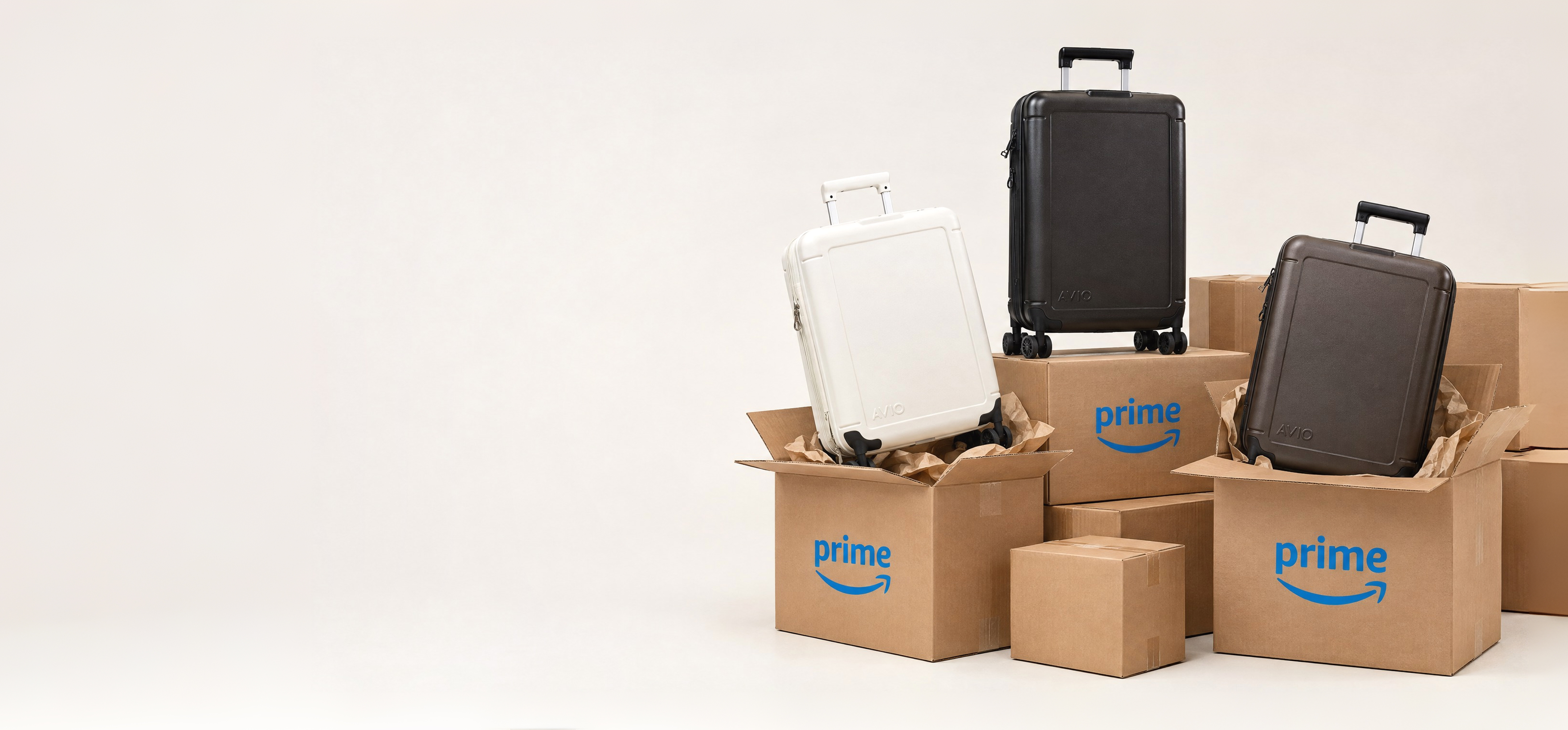 Three rolling suitcases in various colors sit inside and on top of Amazon Prime shipping boxes.