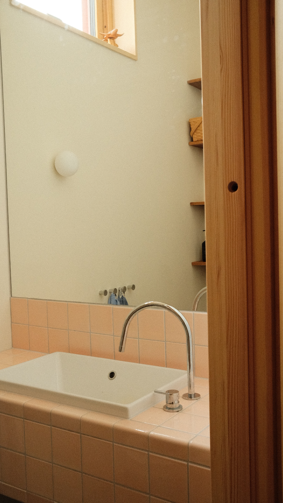 Bathroom sink with a pink tiled countertop and mirror.