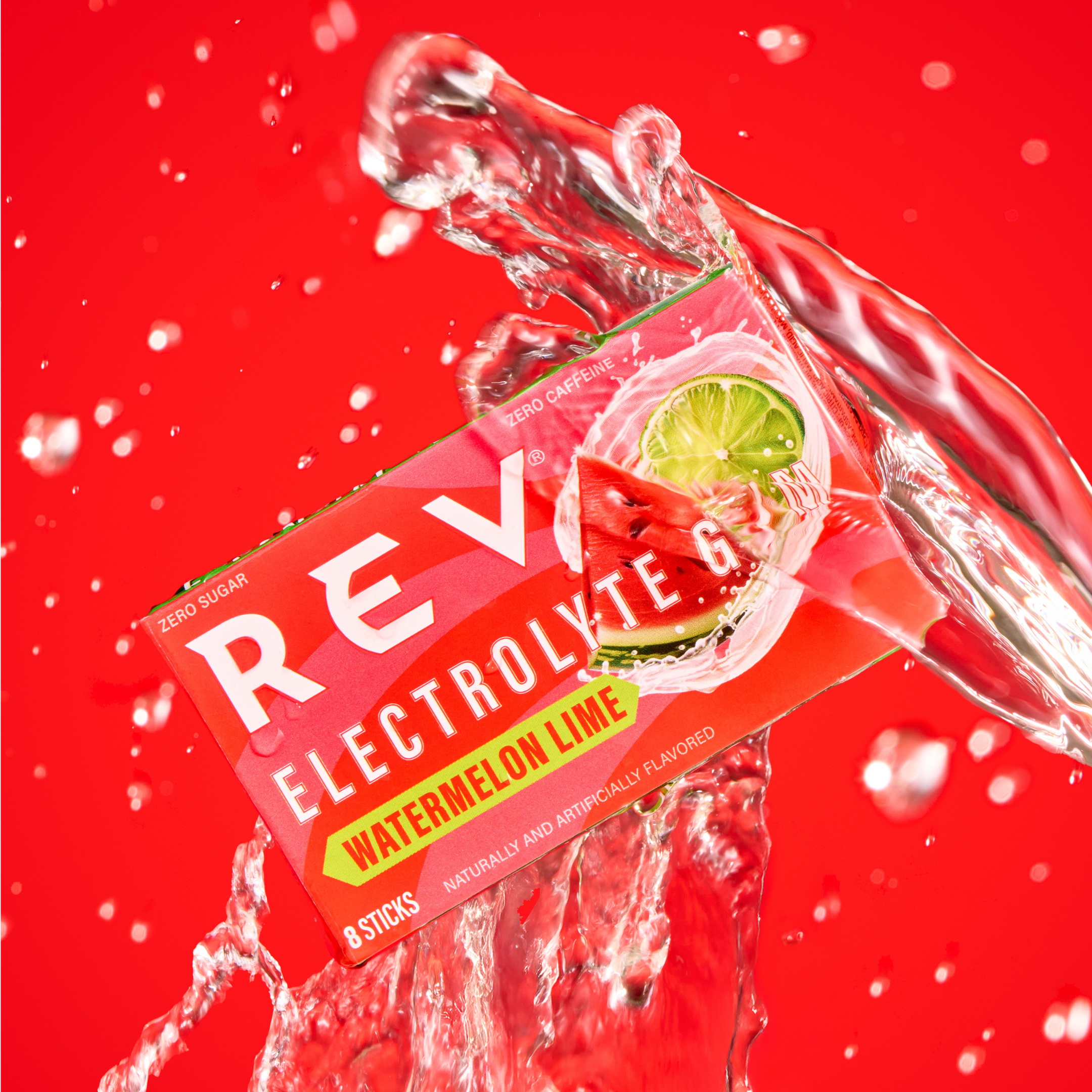 Electrolyte drink packet with watermelon and lime, splashing water on red background.