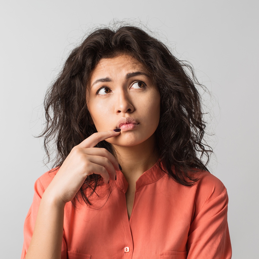 Person in orange shirt looking thoughtful.