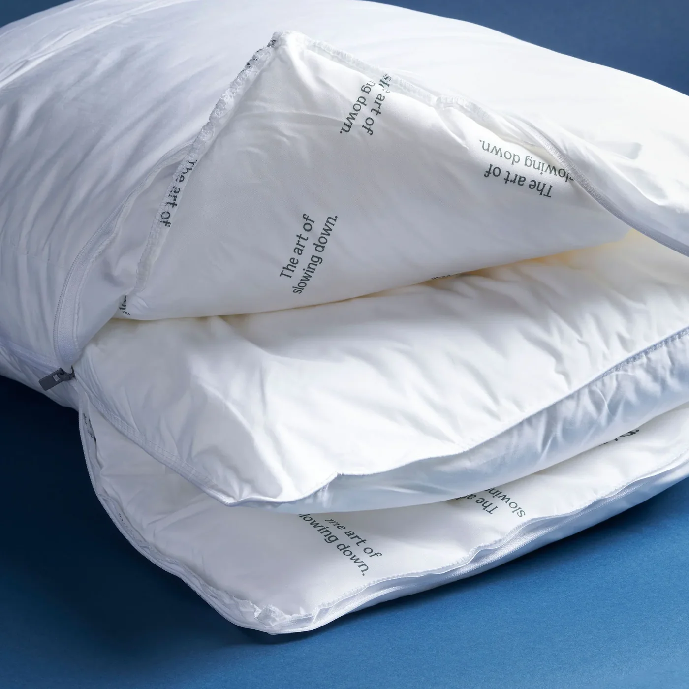 A close-up of a white duvet, unzipped to show the text 'The art of slowing down' inside.