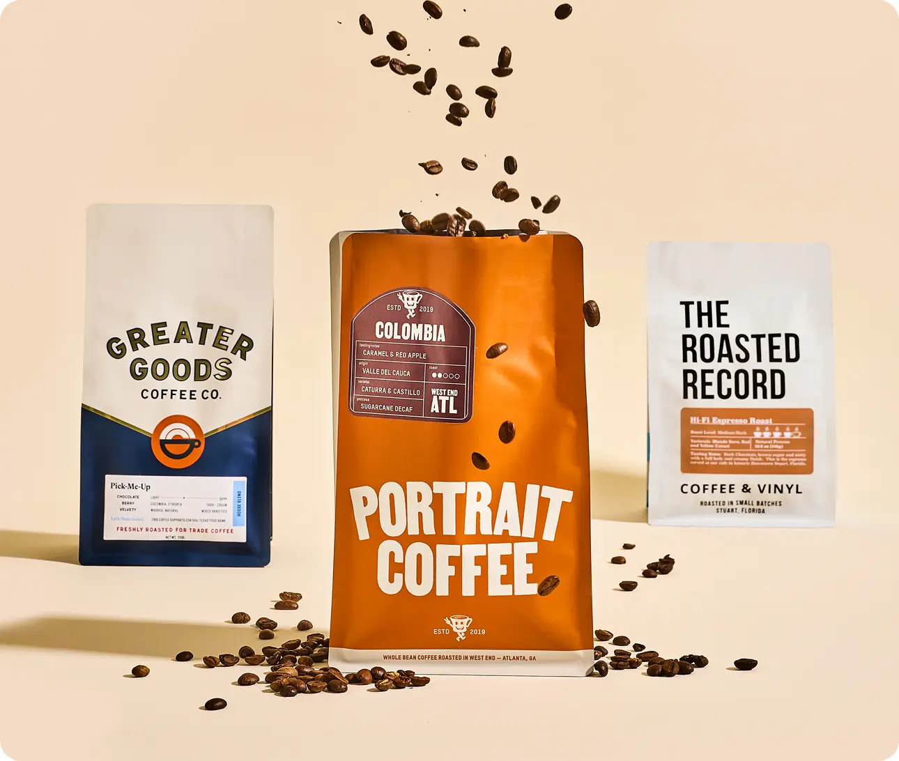 Image of 3 different bags of coffee in a row. The center bag has coffee beans exploding from the top. 