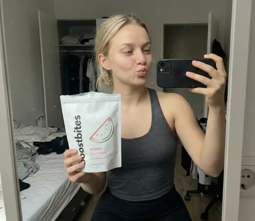 Kundin hält BoostBites Kreatin Gummies Wassermelone – Spiegel-Selfie