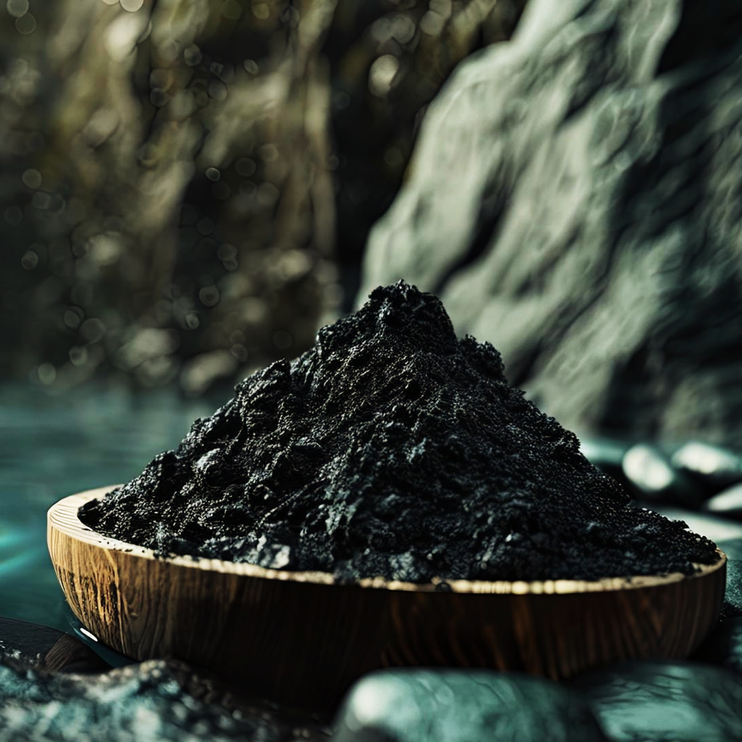 Wooden bowl filled with dark mud near water and rocks.