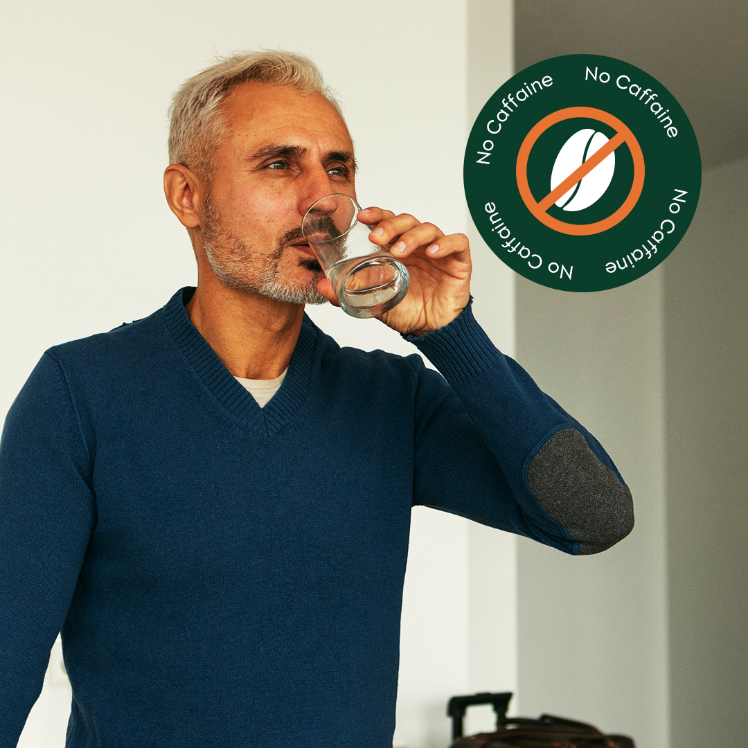 Man in blue sweater drinking water, no caffeine sign present.