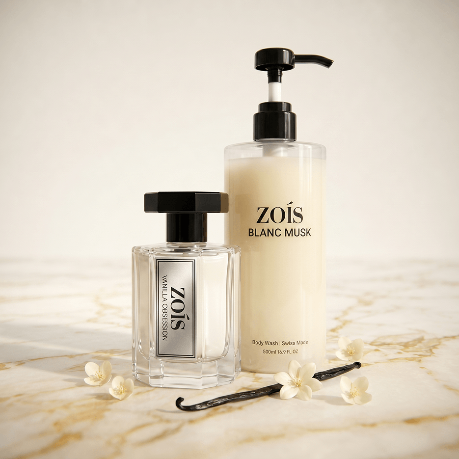 A bottle of Zoís perfume and a pump bottle of body wash sit with vanilla flowers on marble.
