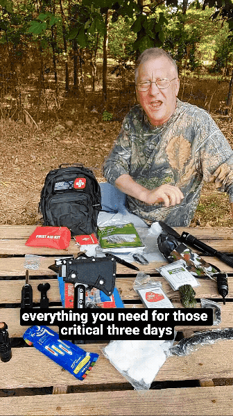 Man displaying emergency supplies on a picnic table outdoors.