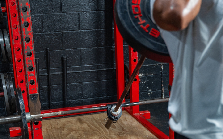 Person lifting weights in a gym with red equipment.