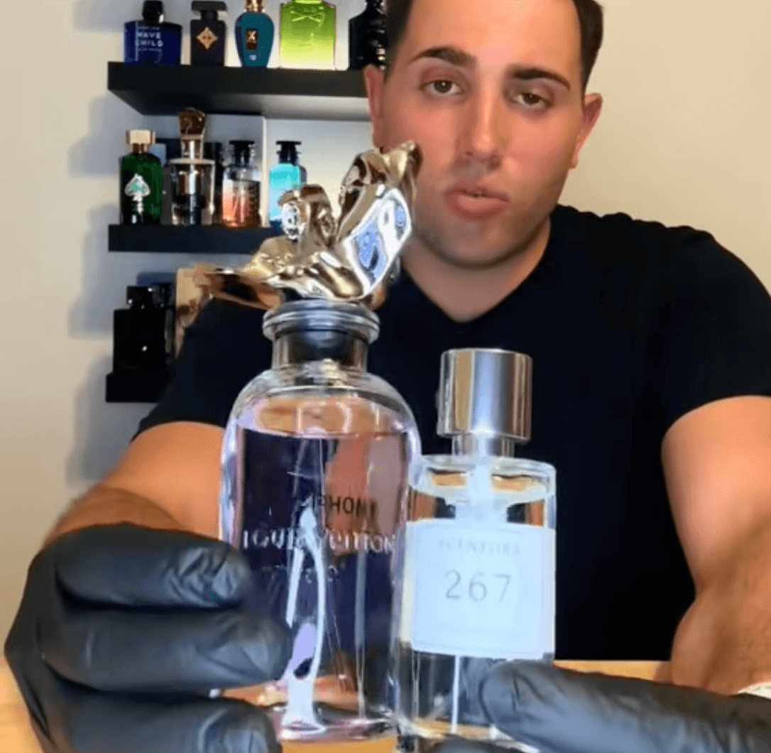 A man in black gloves holds up two bottles of perfume in front of shelves of fragrances.