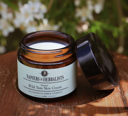 An open jar of Napiers the Herbalists Wild Yam Skin Cream on a wooden surface outdoors.