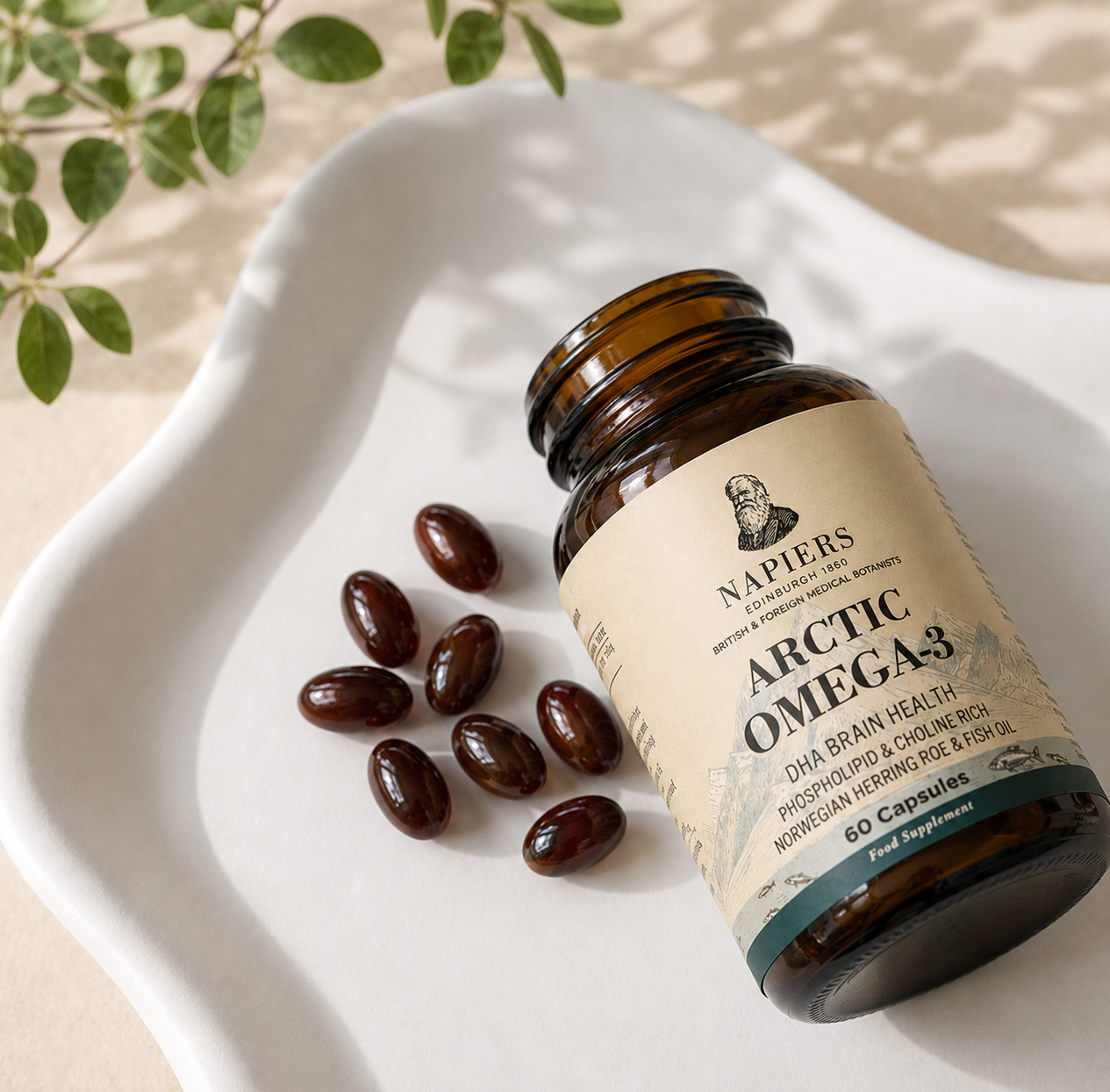 A bottle of Napiers Arctic Omega-3 supplements sits on a white tray with several capsules spilled out.