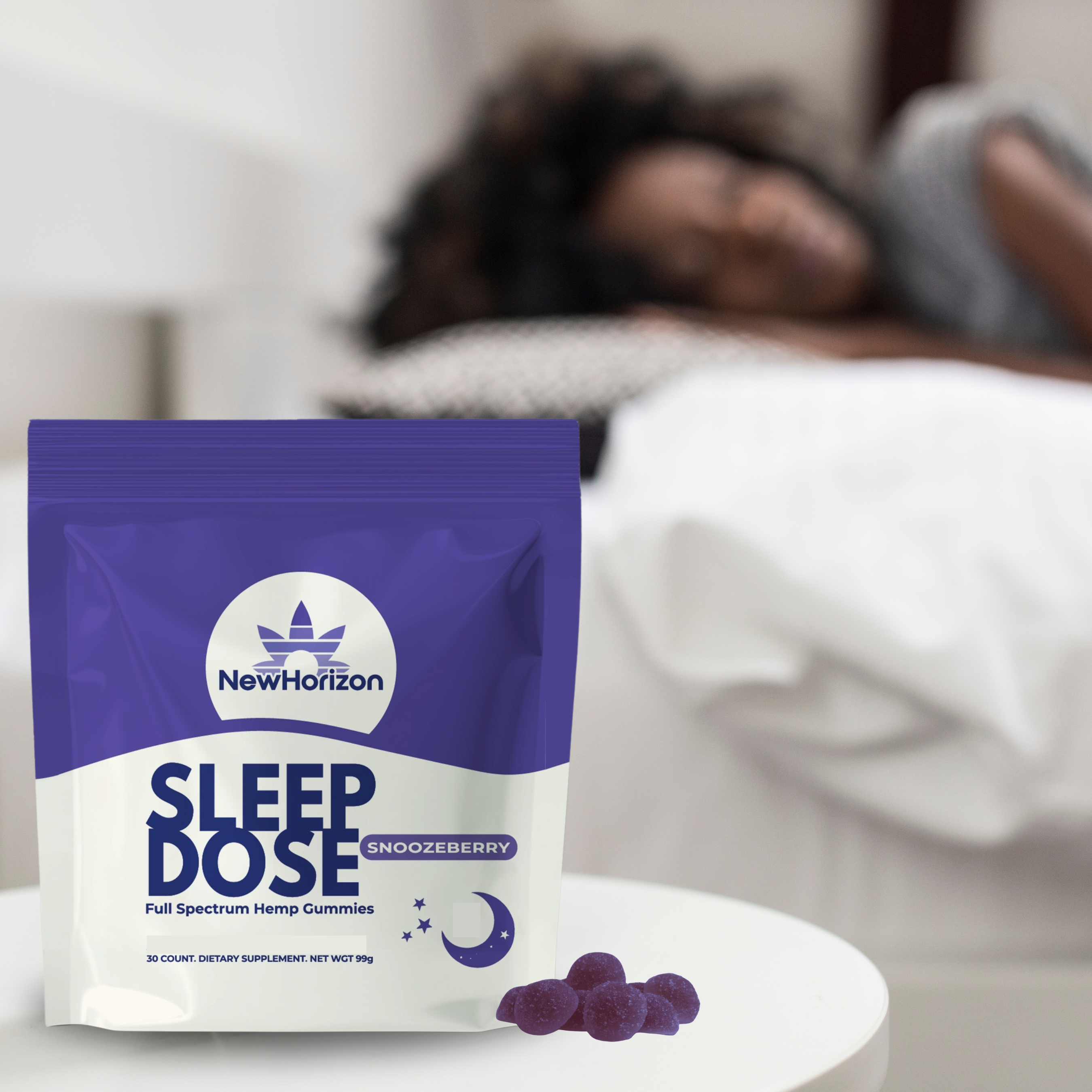 Package of sleep gummies on a table with a person sleeping in the background.