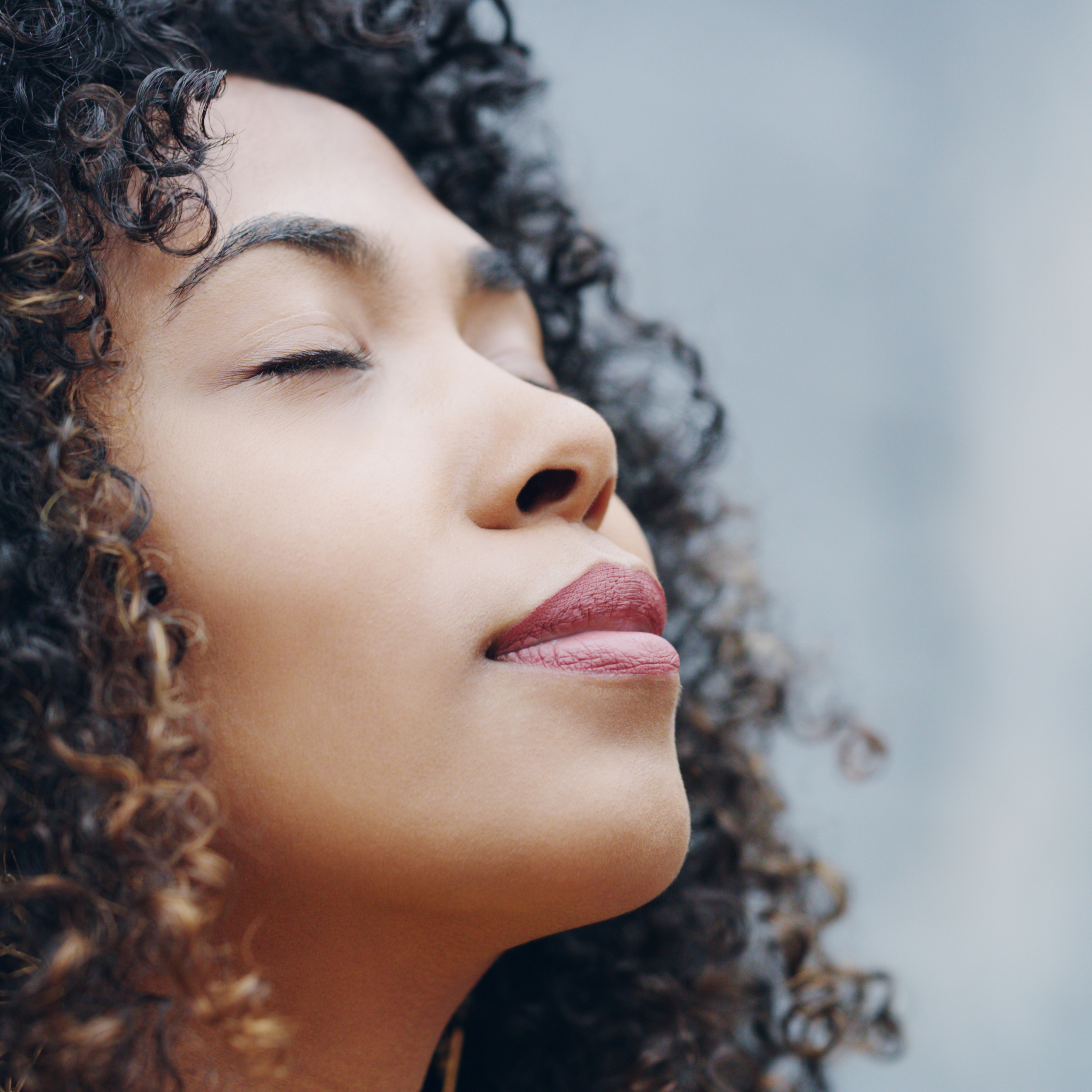Close-up of a person with curly hair and closed eyes.
