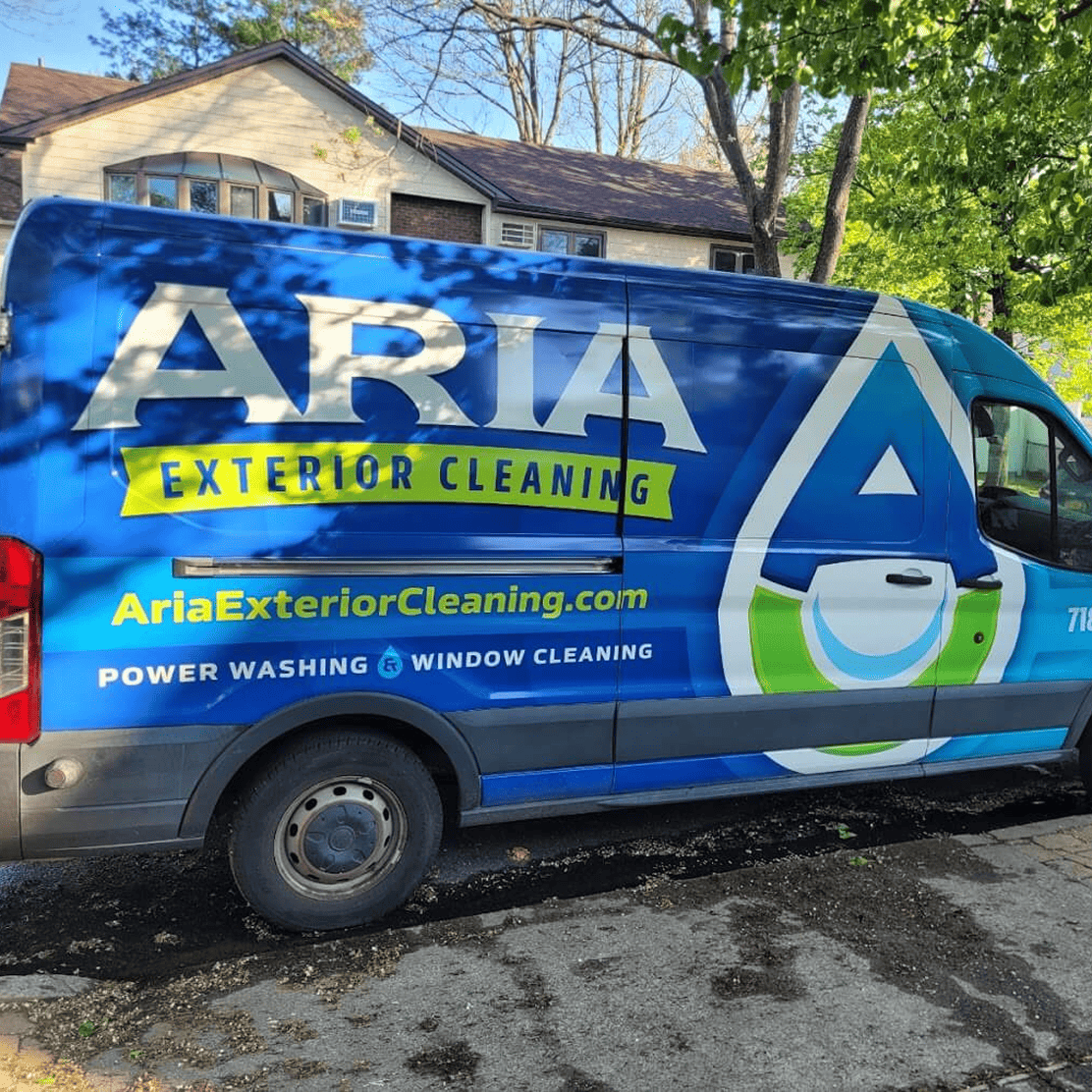 Blue van with 'Aria Exterior Cleaning' logo and website, parked on a residential street.