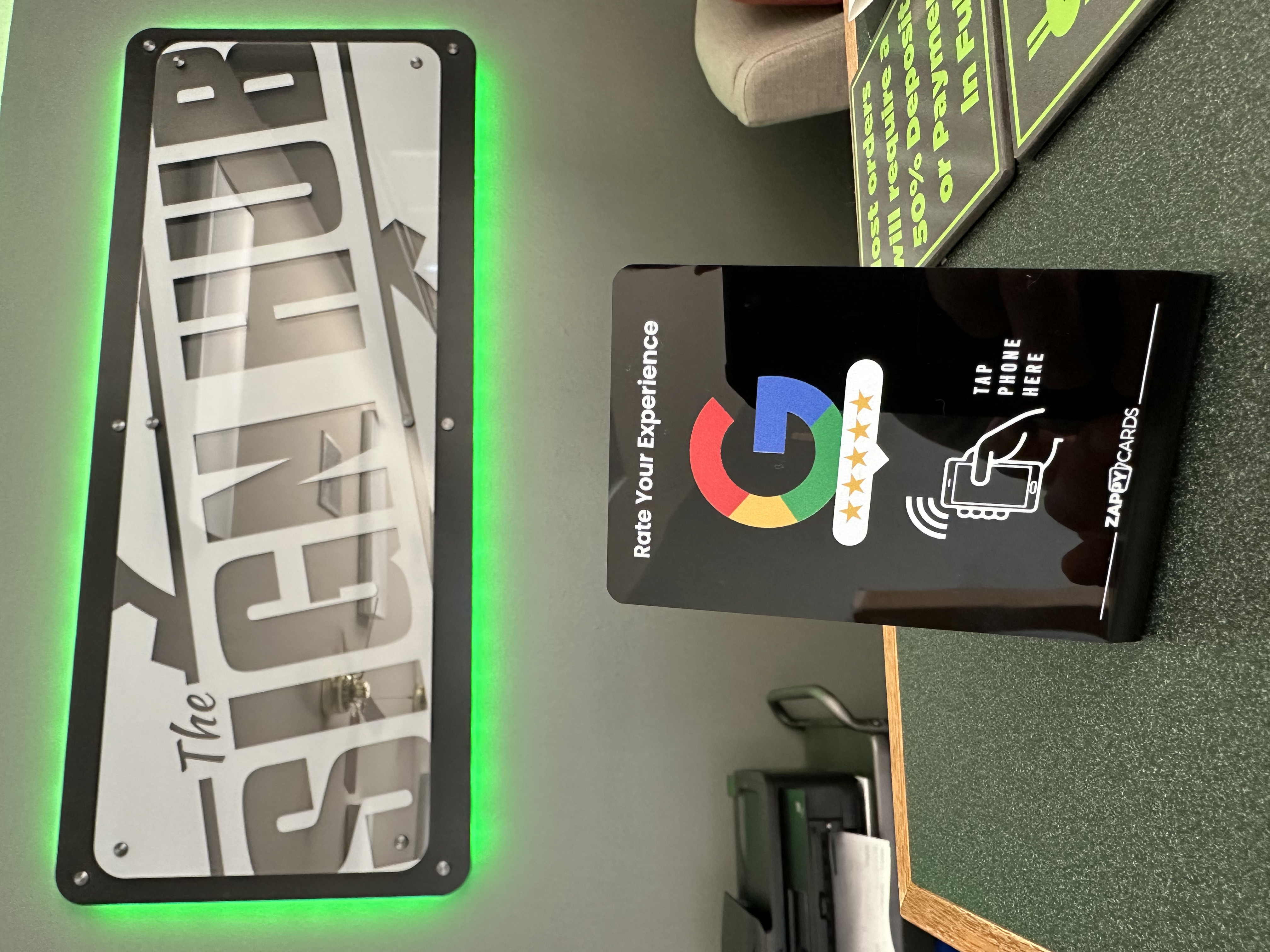 Sign with green lighting and rating stand for phone interaction at a reception desk.