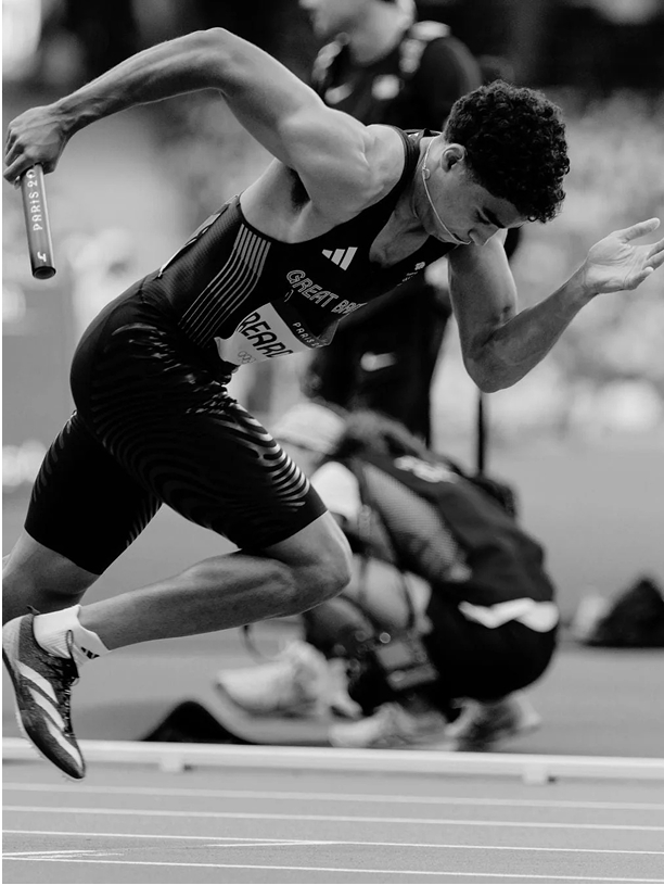 Athlete in motion during a relay race, holding a baton.