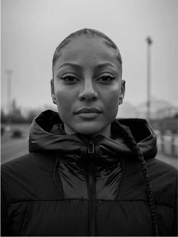 Black and white portrait of a person in a hooded jacket outdoors.