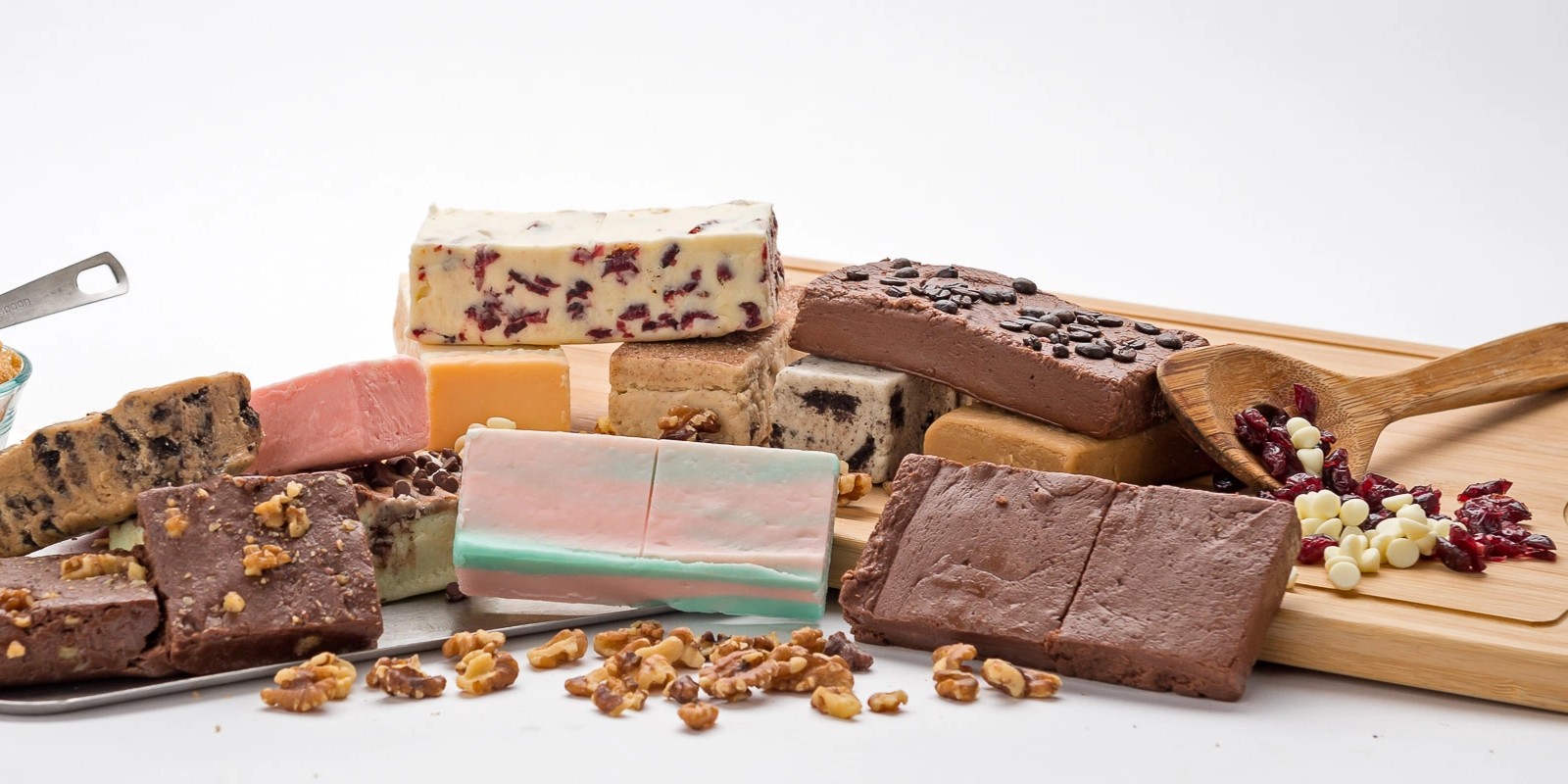 Assorted fudge pieces with nuts and chocolate chips on a wooden board.