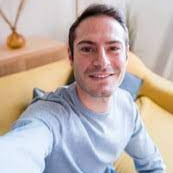 Person taking a selfie on a yellow couch indoors.