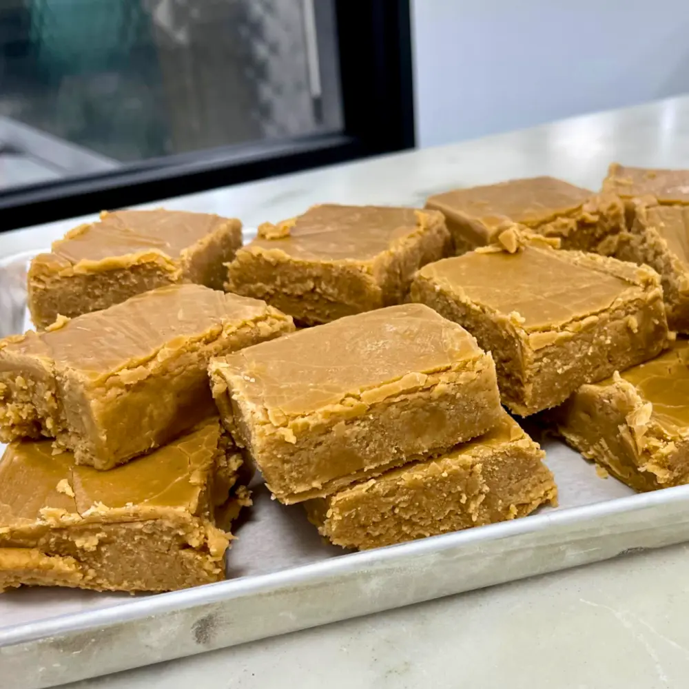 Tray of caramel-colored fudge squares on a countertop.