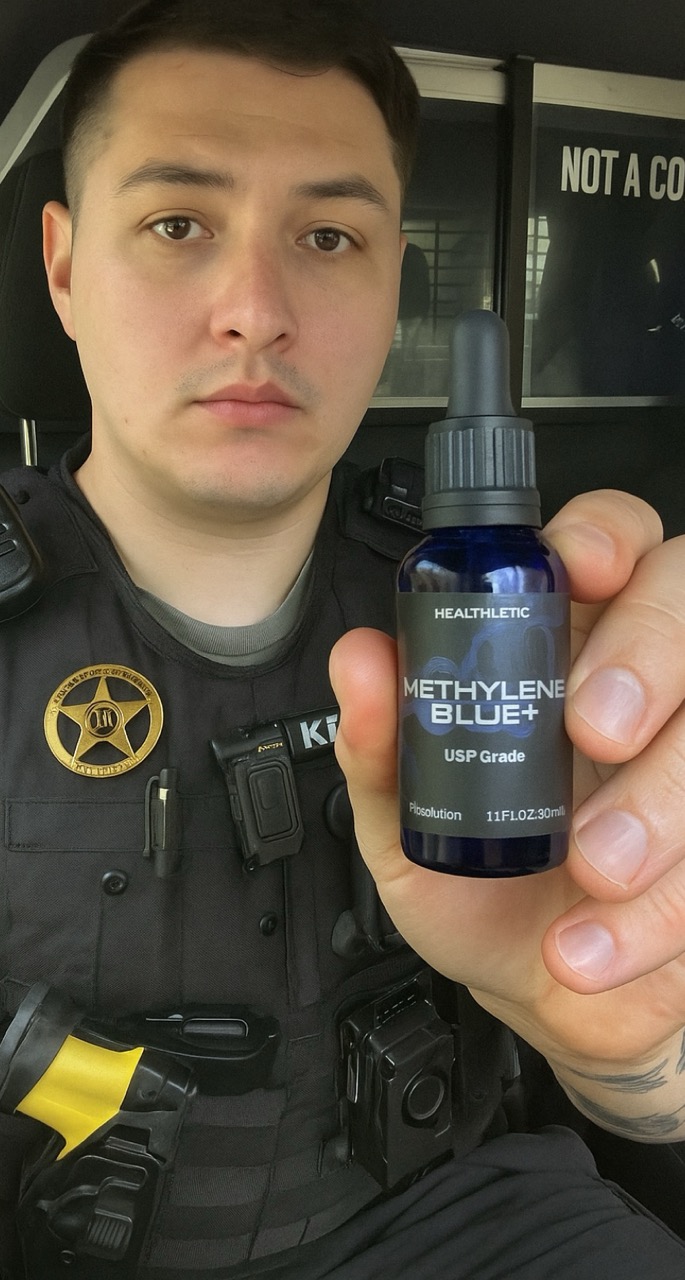 Person in uniform holding a bottle labeled 'Methylene Blue+'. 