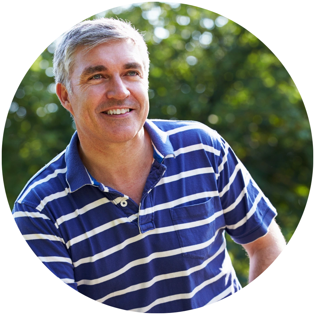 A smiling, gray-haired man in a blue and white striped polo shirt, outdoors.